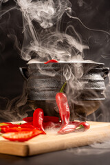 Peppers, beautiful red peppers and a cauldron with smoke over rustic wood, selective focus.