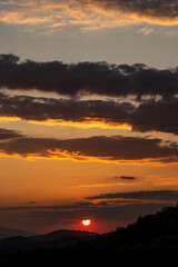 Beautiful sunset in the mountains. Sunset View from the Top of a Mountain. Sunset in strong orange tones in Serbia. The sun falls for horizon, a sunset. Shadows are condensed, beautiful clouds.
