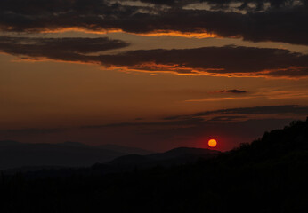 Beautiful sunset in the mountains. Sunset View from the Top of a Mountain. Sunset in strong orange tones in Serbia. The sun falls for horizon, a sunset. Shadows are condensed, beautiful clouds.