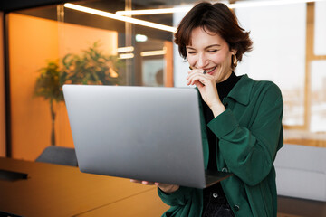 In a lively office, a cheerful female DevOps Engineer joyfully analyzes data with a dynamic team of scientists and financial analysts, sparking enthusiasm among the younger generation