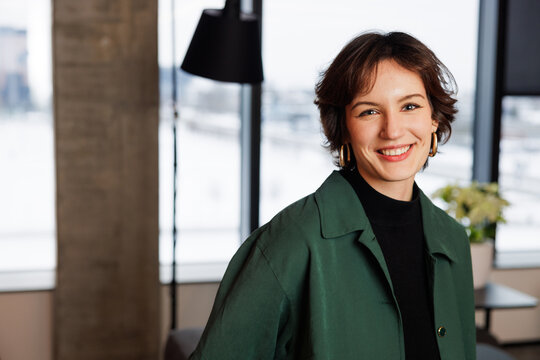 Confident young professional woman working in a modern office. Business trip woman posing for camera for business portraits in green shirt. A young marketing specialist inspired to work