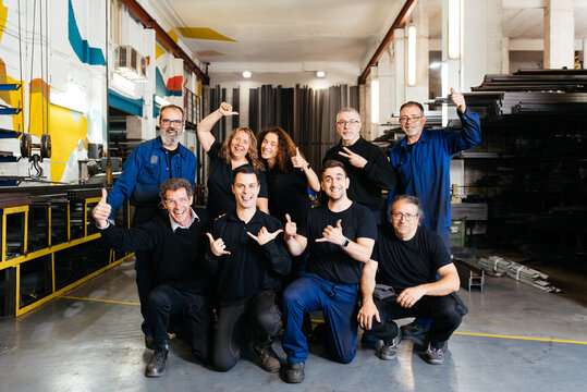 Cheerful group of factory workers in warehouse looking at camera