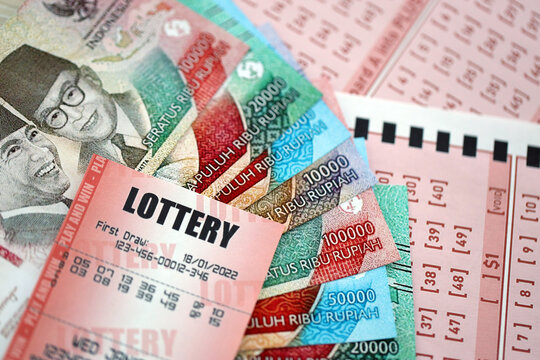 Red lottery ticket lies on pink gambling sheets with indonesian rupiah money bills. Lottery playing concept or gambling addiction in indonesia
