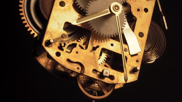 clockwork mechanism of an old ALARM CLOCK  disassembled with golden clockhands turning slowly on silver steel gear movement working closeup low angle shot detail antique watch isolated on black
