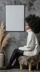 A girl looks at a blank photo frame mockup hanging on a concrete wall inside a bohemian style interior room