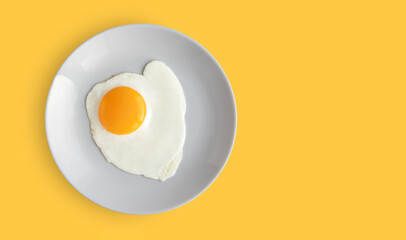 Grey plate with fried egg on bright yellow background. Top view. Copy space