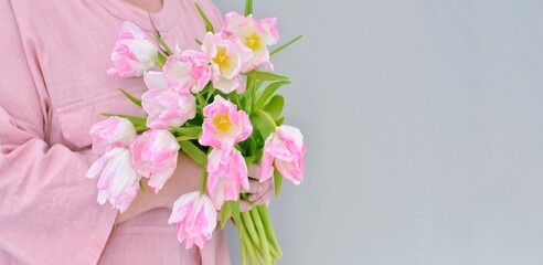 The first spring flowers in the hands of a woman.Pink tulips. A sign of attention and love,flower compliment.