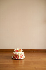White chocolate cake with cherries and cream cheese for a children birthday stands on a plate on the floor in the room