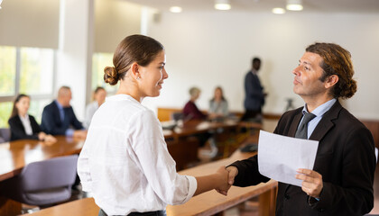 Businessman shakes hands with a businesswoman and congratulates her on a job well done