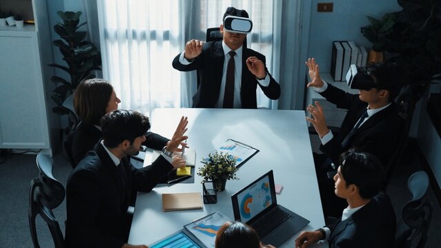 Top view of manager working on laptop and sending data analysis to business people by using VR glass headset while diverse team planning marketing strategy and looking at financial graph. Directorate.
