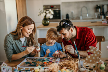 Parents and daughter share laughs while decorating Easter eggs