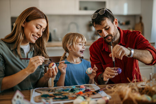 Loving caucasian family of three bonds over Easter egg decorating in their cozy dining room
