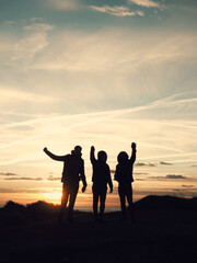 Fototapeta premium Three friends on the beach dunes with the sunset in the background. 