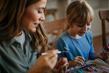 Mom and daughter decorating eggs in their dining space