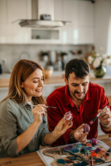 Happy couple adding colorful touches to their Easter decorations at home