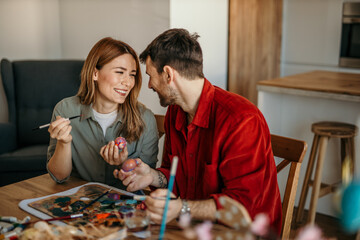 Happy couple adding colorful touches to their Easter decorations at home
