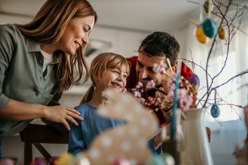 Parents and daughter joyfully preparing for Easter with colorful decorations