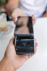 Hand of man making mobile payment in coffee shop