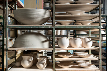 Handmade ceramic in the ceramist's workshop. Stoneware plates, vases and bowls on the shelf