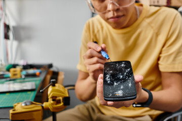 cropped view of technical expert with screwdriver and smartphone with broken touchscreen in workshop