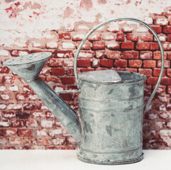 old zinc water can infront of brick wall