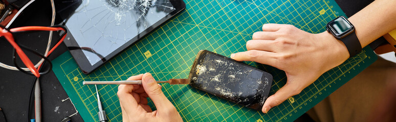 partial view of technician disconnecting broken touchscreen of smartphone in repair workshop, banner