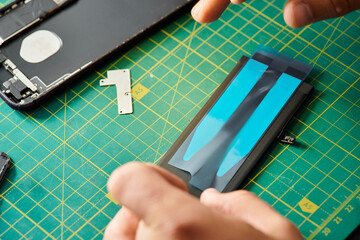 cropped view of technician working with battery of mobile phone in repair shop, repair service