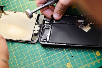cropped view of repairman assembling mobile phone after reparation in workshop, small business