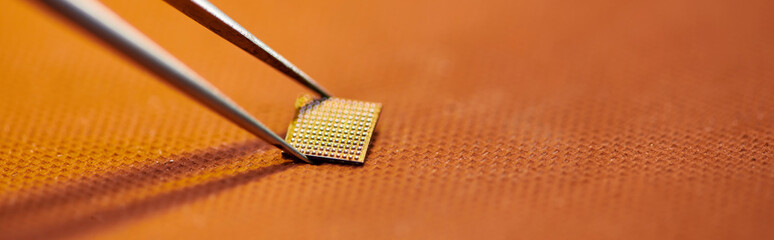 close up view of electronic microscheme and tweezers on table in repair shop, horizontal banner
