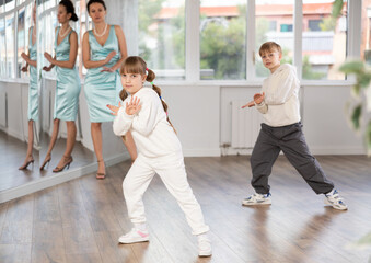 Fototapeta premium Energetic happy tween dancers, girl and boy rehearsing popping techniques during workout in modern street dance studio. Concept of self-expression of typical generation Alpha