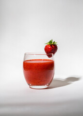 Glass with strawberries, red smoothie and on a white background. Strawberries on the glass. Summer drink. Vitamins, diet, proper nutrition, vegan