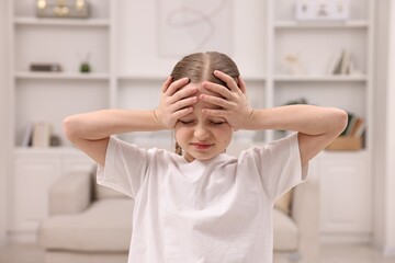 Little girl suffering from headache at home