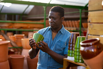 Portrait of a african american man choosing flower pots for indoor plants at the gardening market
