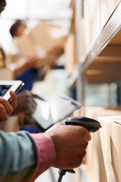 African american distribution warehouse worker arm scanning cardboard box code. Logistics manager cheking goods in stock using barcode scanner on freight parcels in storehouse