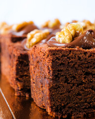 Close up of a chocolate brownie with cocoa and hazelnut cream and nuts on top.