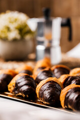 Chocolate croissants on a white plate with an Italian coffee machine over a white and brown background
