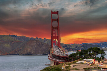 The Golden Gate Bridge over the bay with mountains and lush green trees, plants and grass at the...