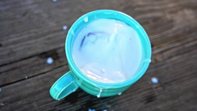 Chocolate covered pretzel falling inside mug with milk in slow motion