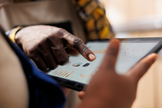 African american warehouse worker hand pointing at inventory statistics on tablet. Storehouse employee asking supervisor about products distribution analytics report and tapping on screen close up