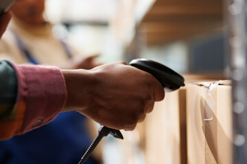 African american storehouse employee arm using barcode scanner on cardboard box. Warehouse operator...