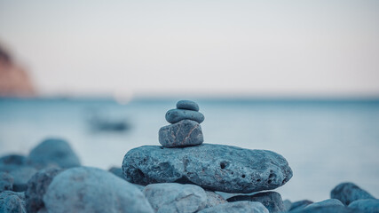 Pyramid stones on the seashore on the blue sea background. Calm sea, travel destination for...