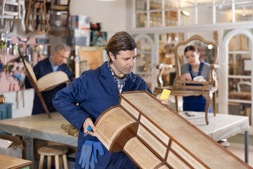 Male furniture maker sanding vintage commode in workshop - obrazy, fototapety, plakaty