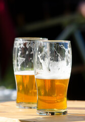 two glasses of craft lager beer on wooden table with blur background