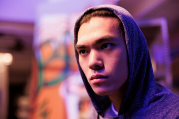 Focused asian hacker in hood hacking server and cracking complex password. Cocentrated young...