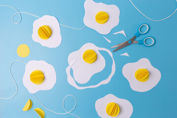 three fried eggs paper craft hanging from a string on a blue background, easter decoration concept, 