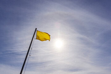 yellow flag against blue sky, 
caution if you choose to swim