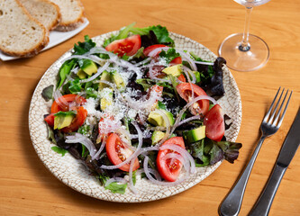 Fresh salad with avocado, onion, cheese and tomatoes served on plate..