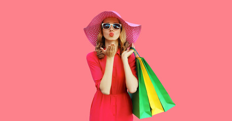 Portrait of beautiful young woman model blow kiss posing with colorful shopping bags in summer hat