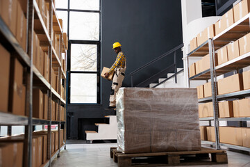 African american shipping company loader carrying heavy parcel downstairs. Post office man employee...