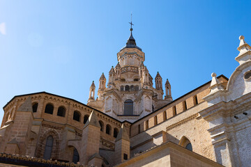 Fototapeta premium Impressive architecture of ancient Roman Catholic Cathedral Santa Maria de Huerta in Tarazona with dome tower decorated with turrets in Aragonese Mudejar style against blue sky on sunny day, Spain